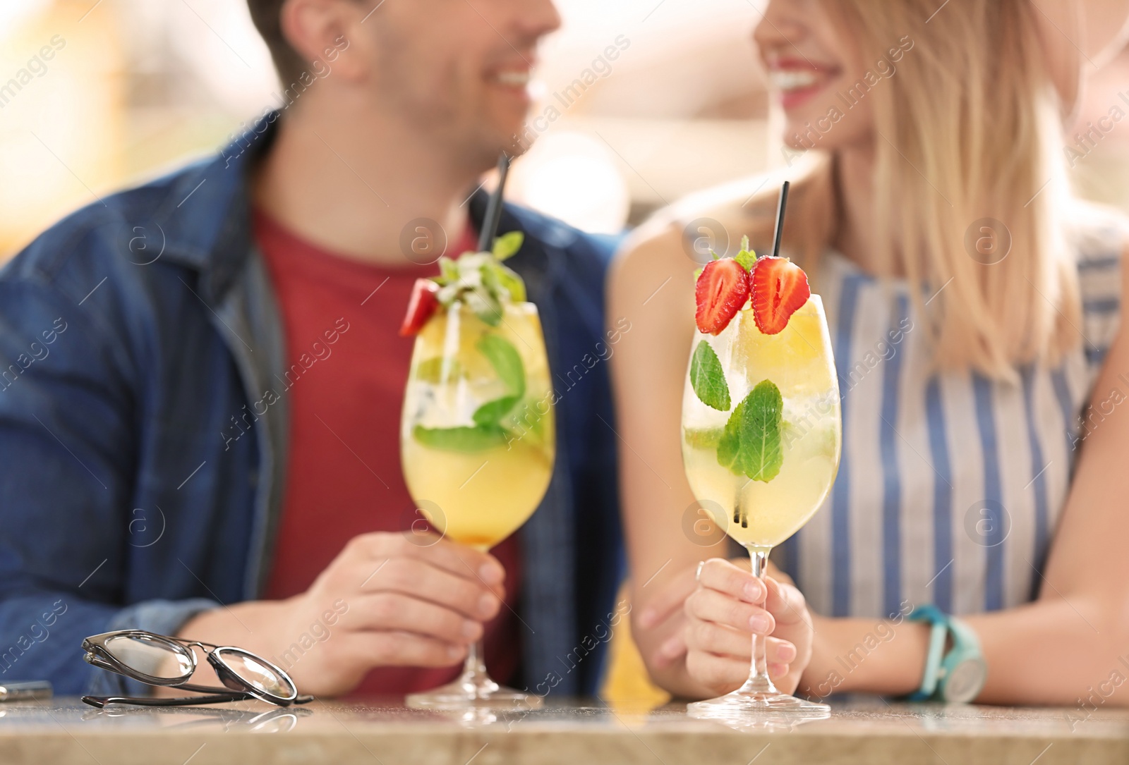 Photo of Young couple with glasses of tasty lemonade in open-air cafe