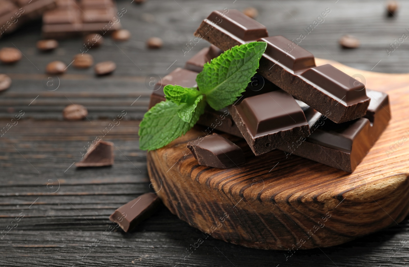 Photo of Pieces of dark chocolate with mint on wooden table