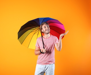 Photo of Man with rainbow umbrella on color background