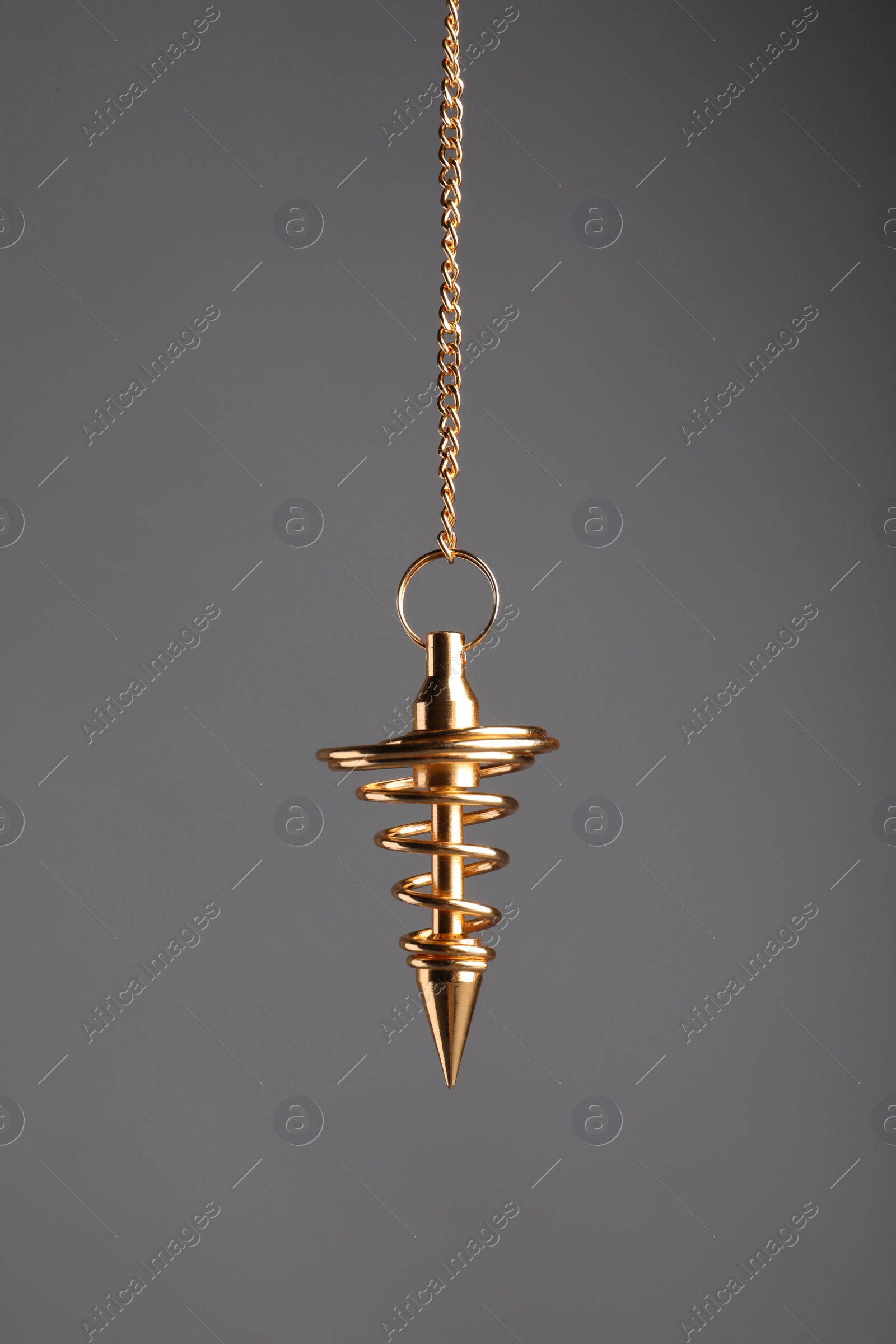 Photo of Stylish pendulum on grey background. Hypnotherapy session