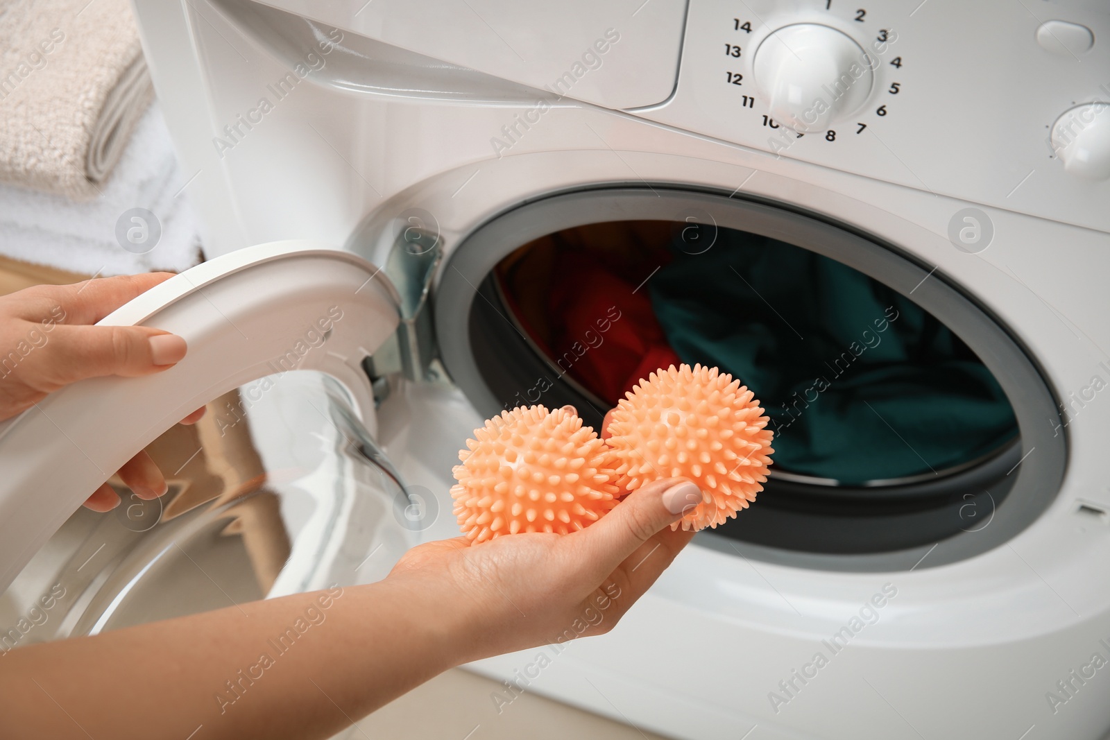 Photo of Woman putting dryer balls into washing machine, closeup