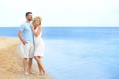 Happy romantic couple spending time together on beach, space for text