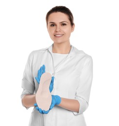 Beautiful female orthopedist showing insole on white background