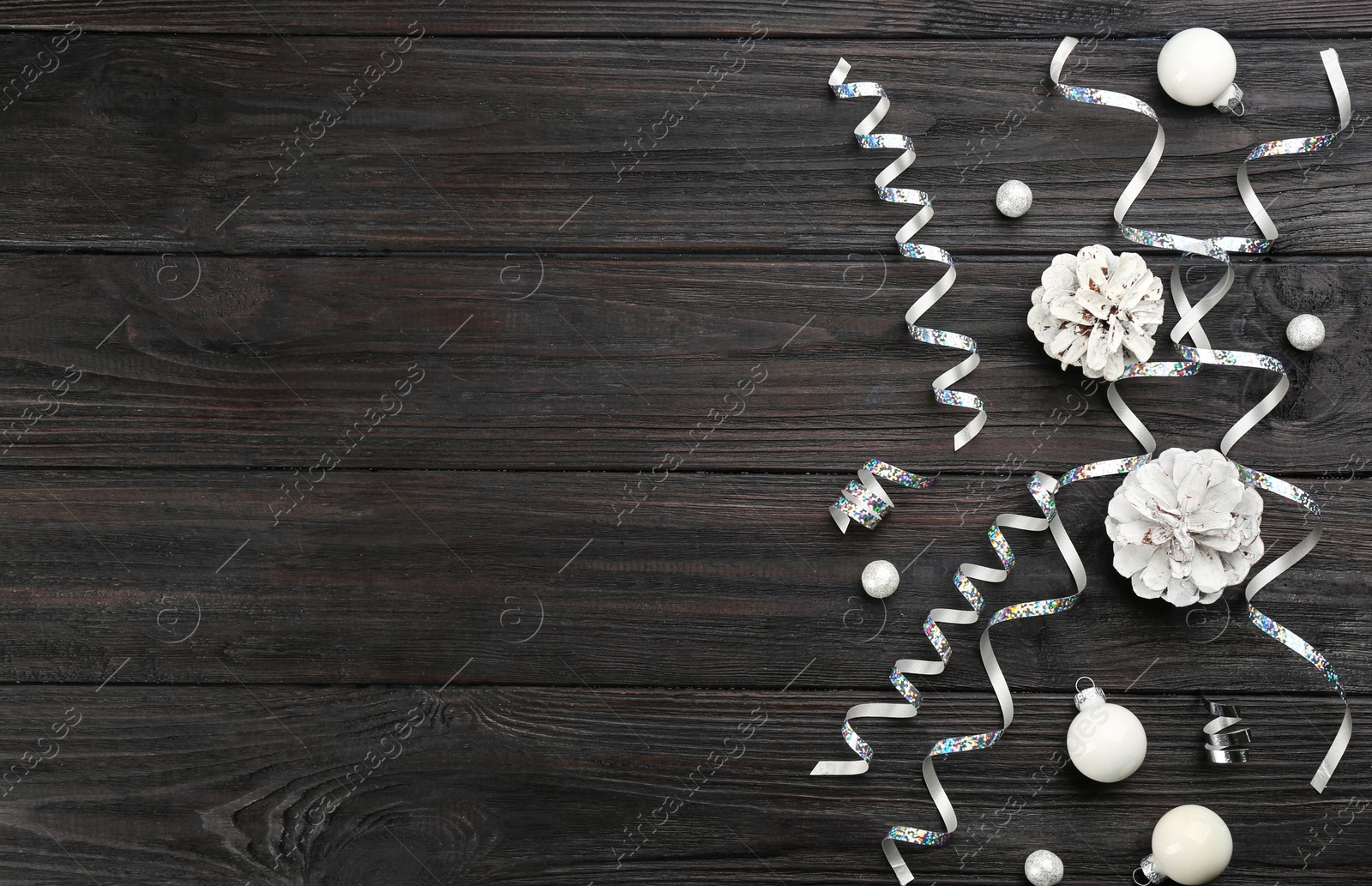 Photo of Flat lay composition with serpentine streamers and Christmas decor on black wooden background. Space for text