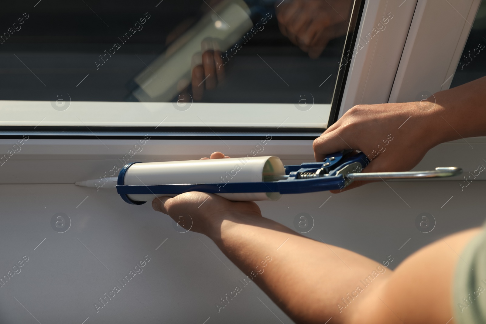 Photo of Construction worker sealing window with caulk, closeup