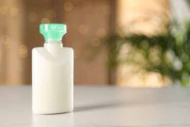 Photo of Mini bottle of cosmetic product on white table against blurred background. Space for text