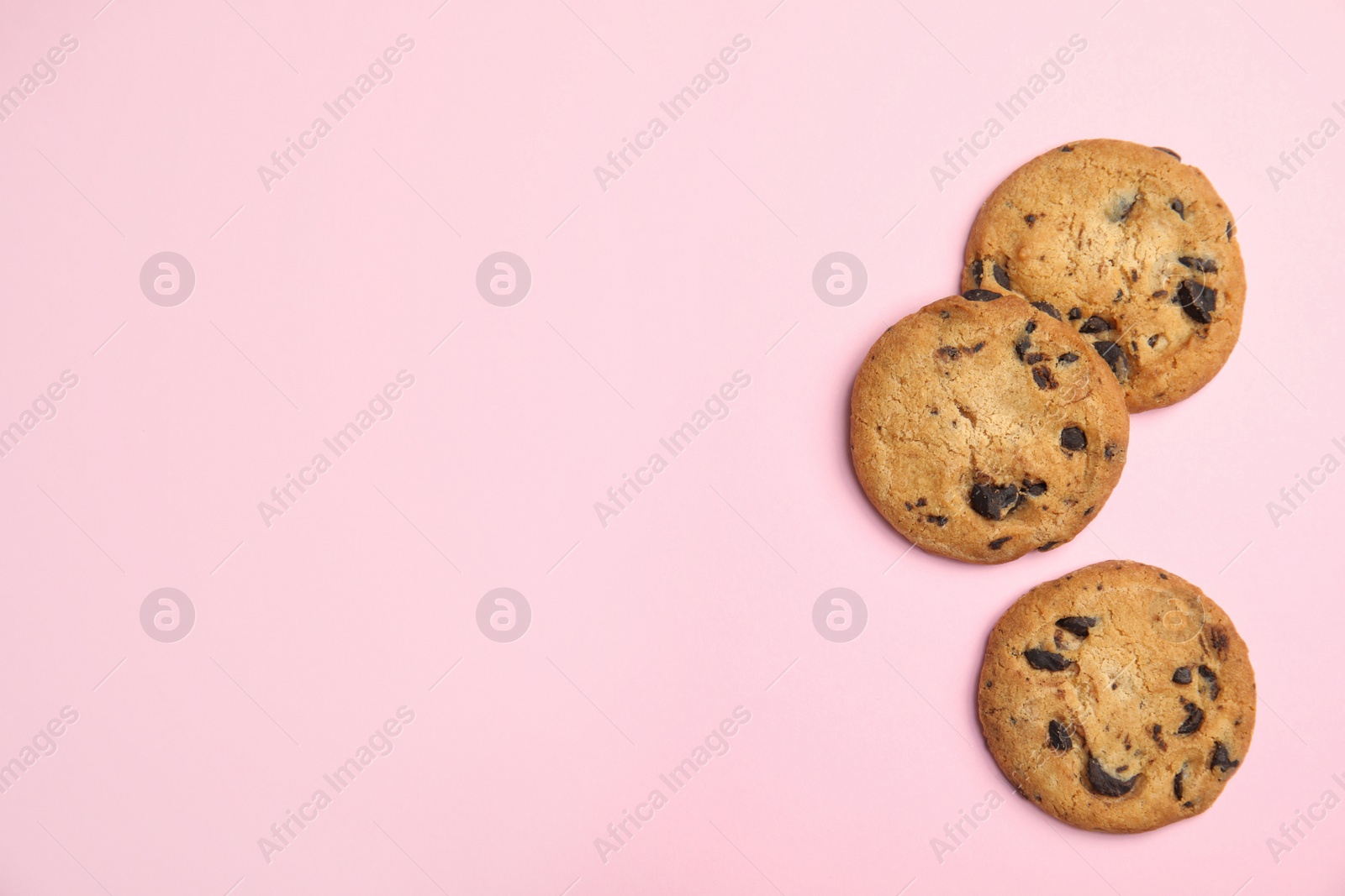 Photo of Delicious chocolate chip cookies on color background, flat lay. Space for text