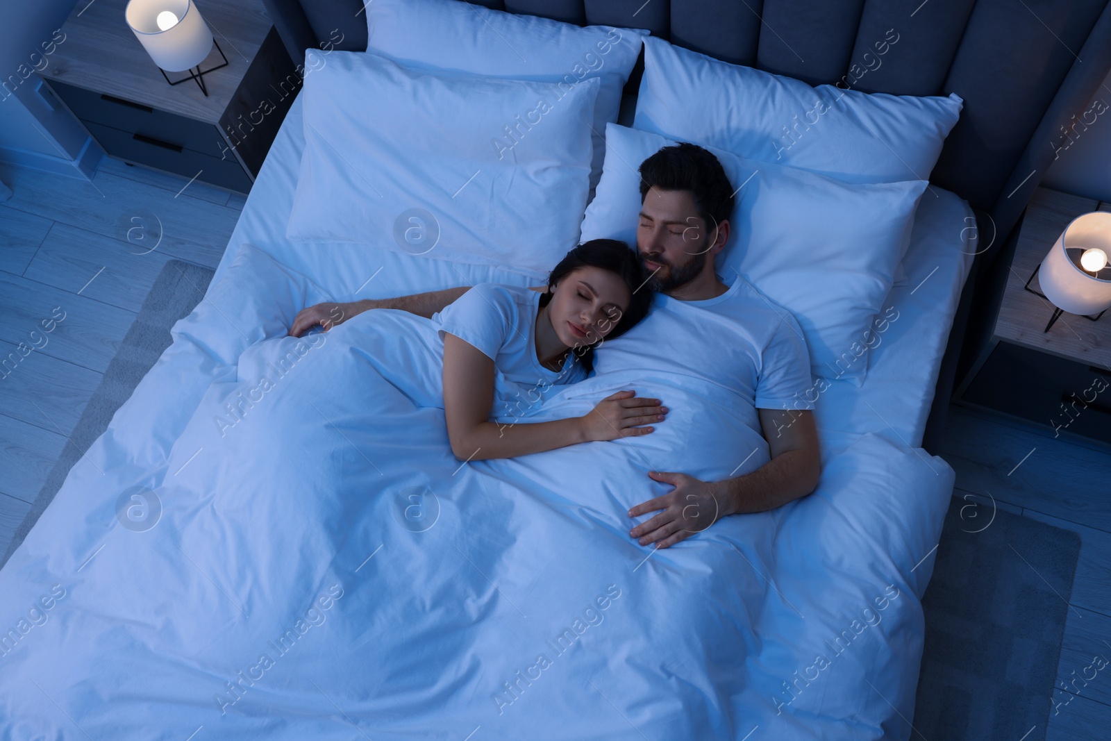 Photo of Lovely couple sleeping together in bed at night, top view