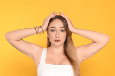 Photo of Young woman with lip and ear piercings on yellow background