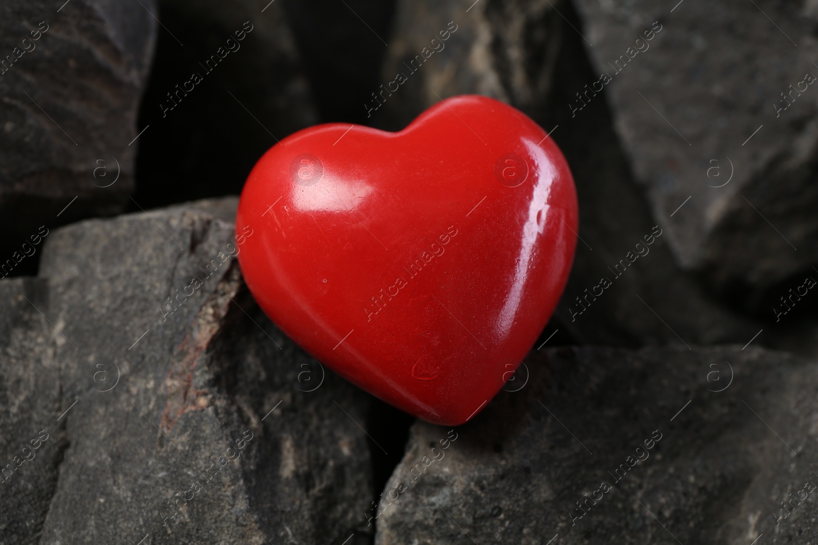 Photo of One red decorative heart on stones, closeup