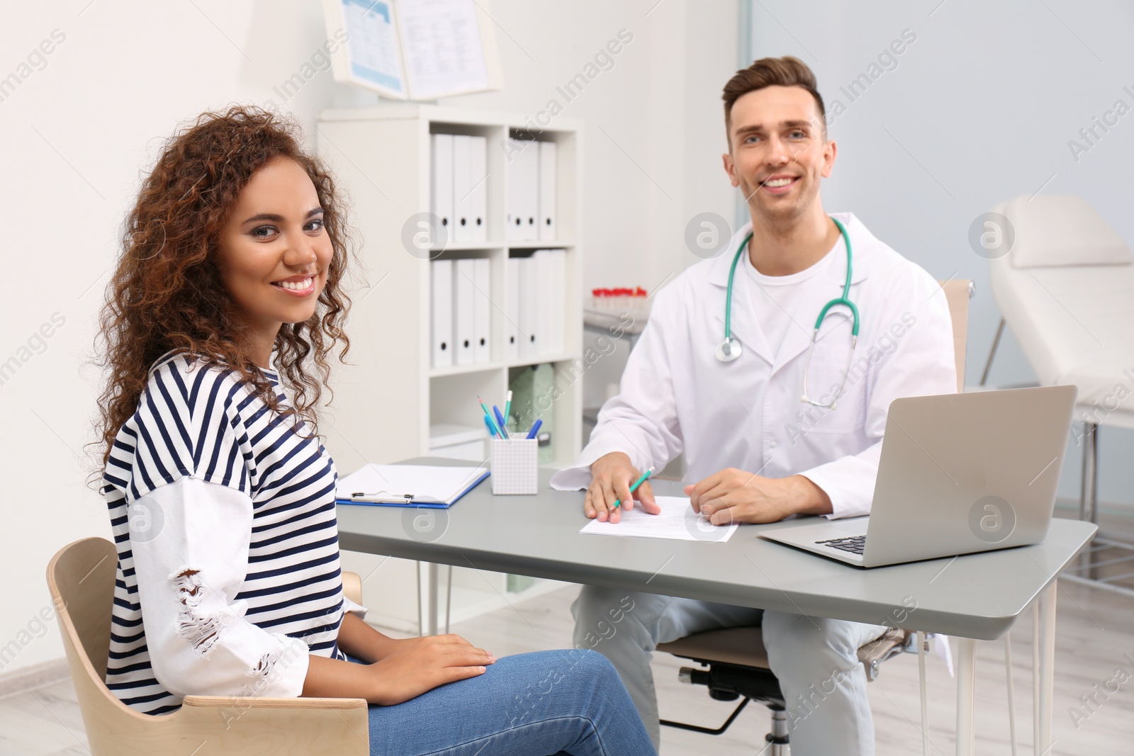 Photo of Male doctor working with African American patient in hospital