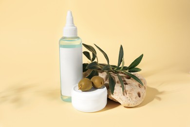 Photo of Cosmetic products and olives on beige background