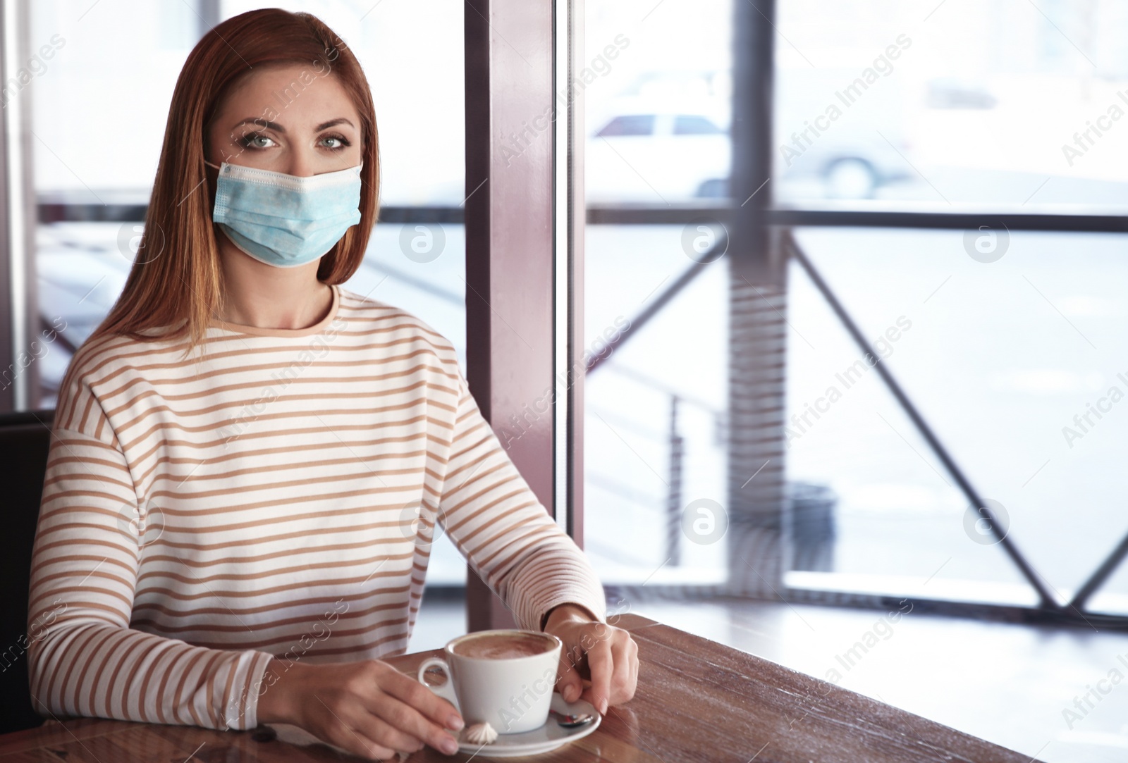 Photo of Woman with medical mask in cafe. Virus protection