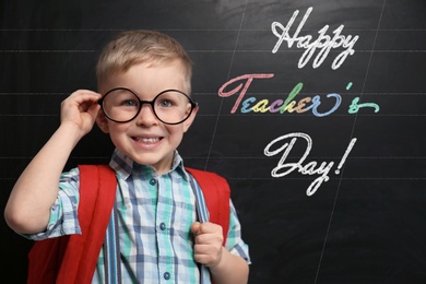 Cute little child wearing glasses near chalkboard with text Happy Teacher's Day