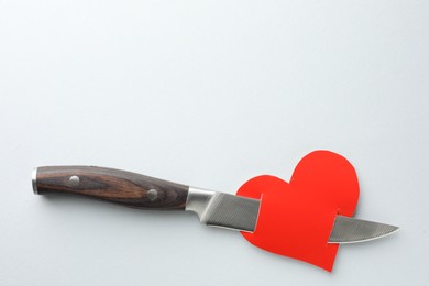Photo of Broken heart. Red paper heart pierced with knife on white background, top view. Space for text