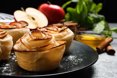 Photo of Freshly baked apple roses on grey table, closeup. Beautiful dessert