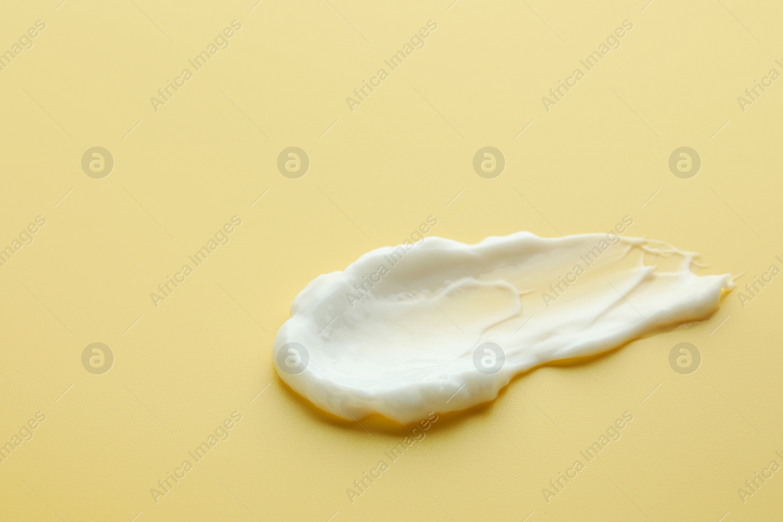 Photo of Sample of face cream on yellow background