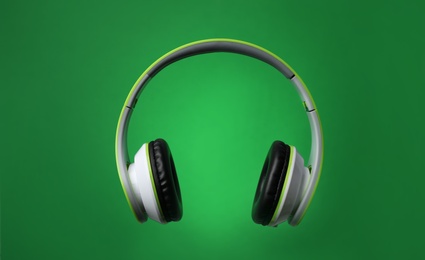 Stylish modern headphones with earmuffs on color background