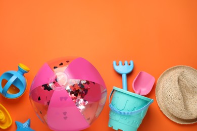 Photo of Flat lay composition with beach ball and sand toys on orange background, space for text