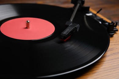 Photo of Modern vinyl record player with disc on table, closeup