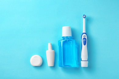 Photo of Flat lay composition with electric toothbrush and oral hygiene products on color background