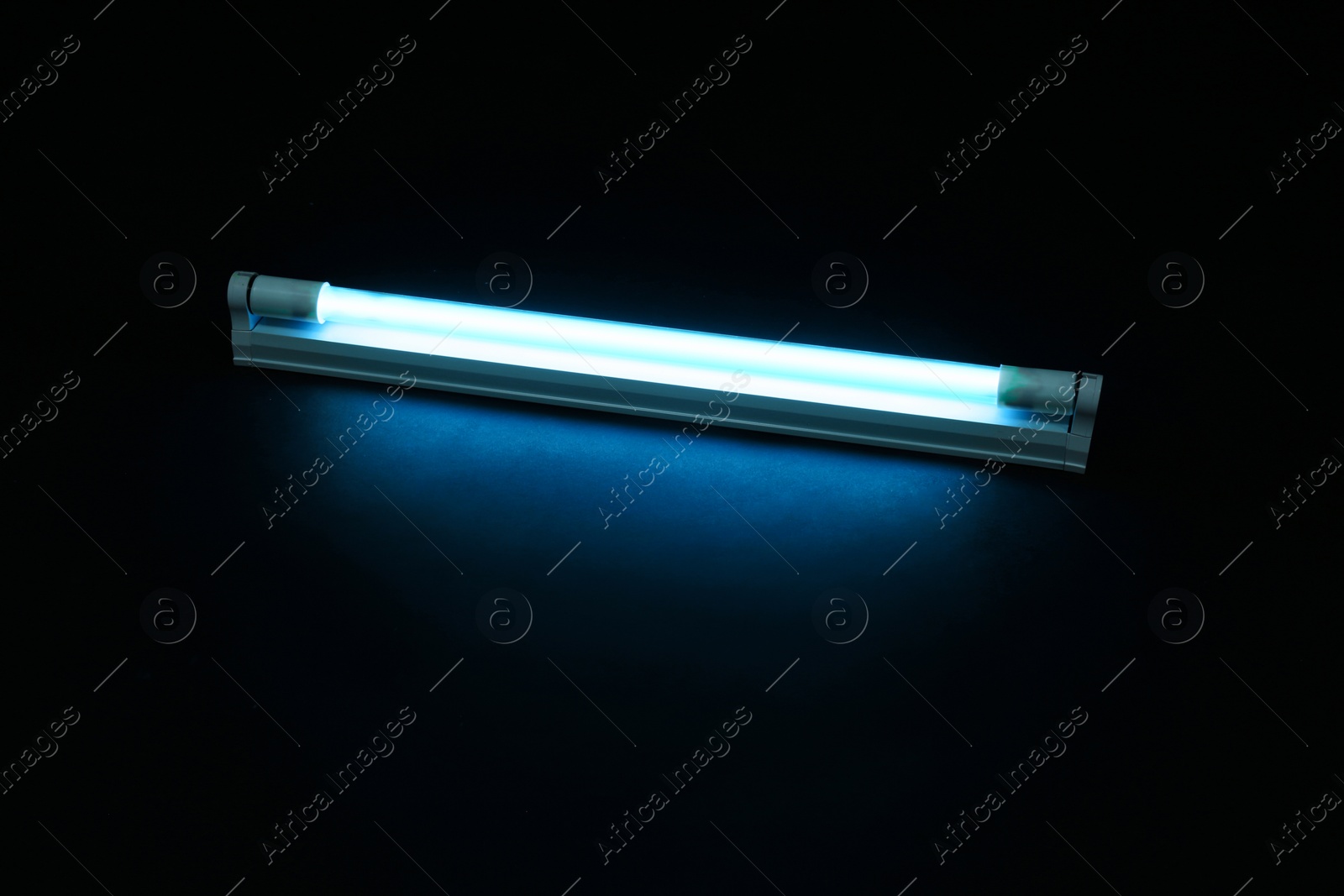 Photo of Modern ultraviolet lamp glowing on black background