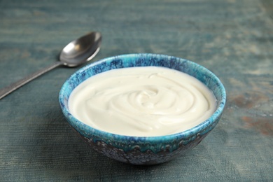 Photo of Bowl with creamy yogurt on blue wooden background