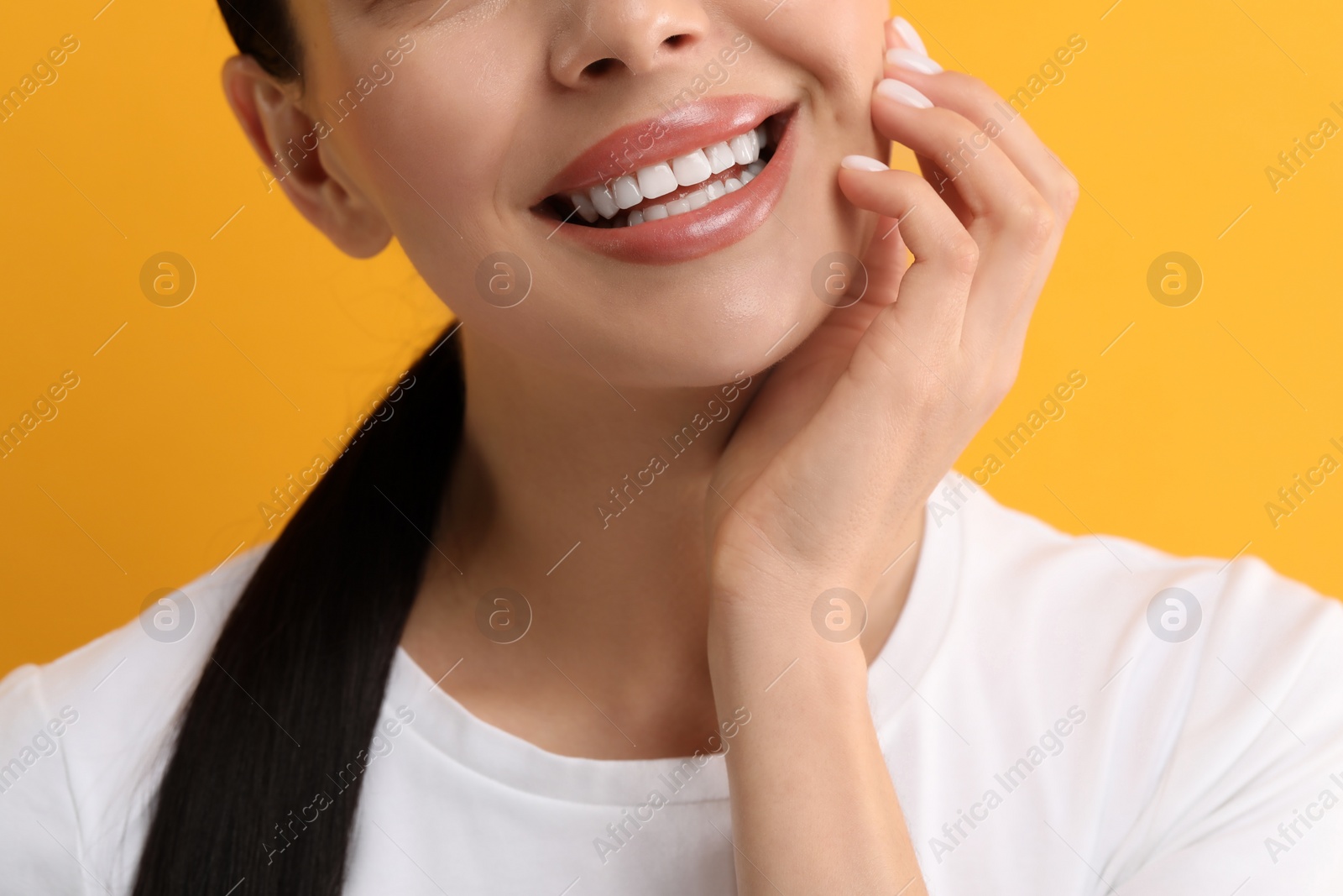 Photo of Woman with clean teeth smiling on yellow background, closeup