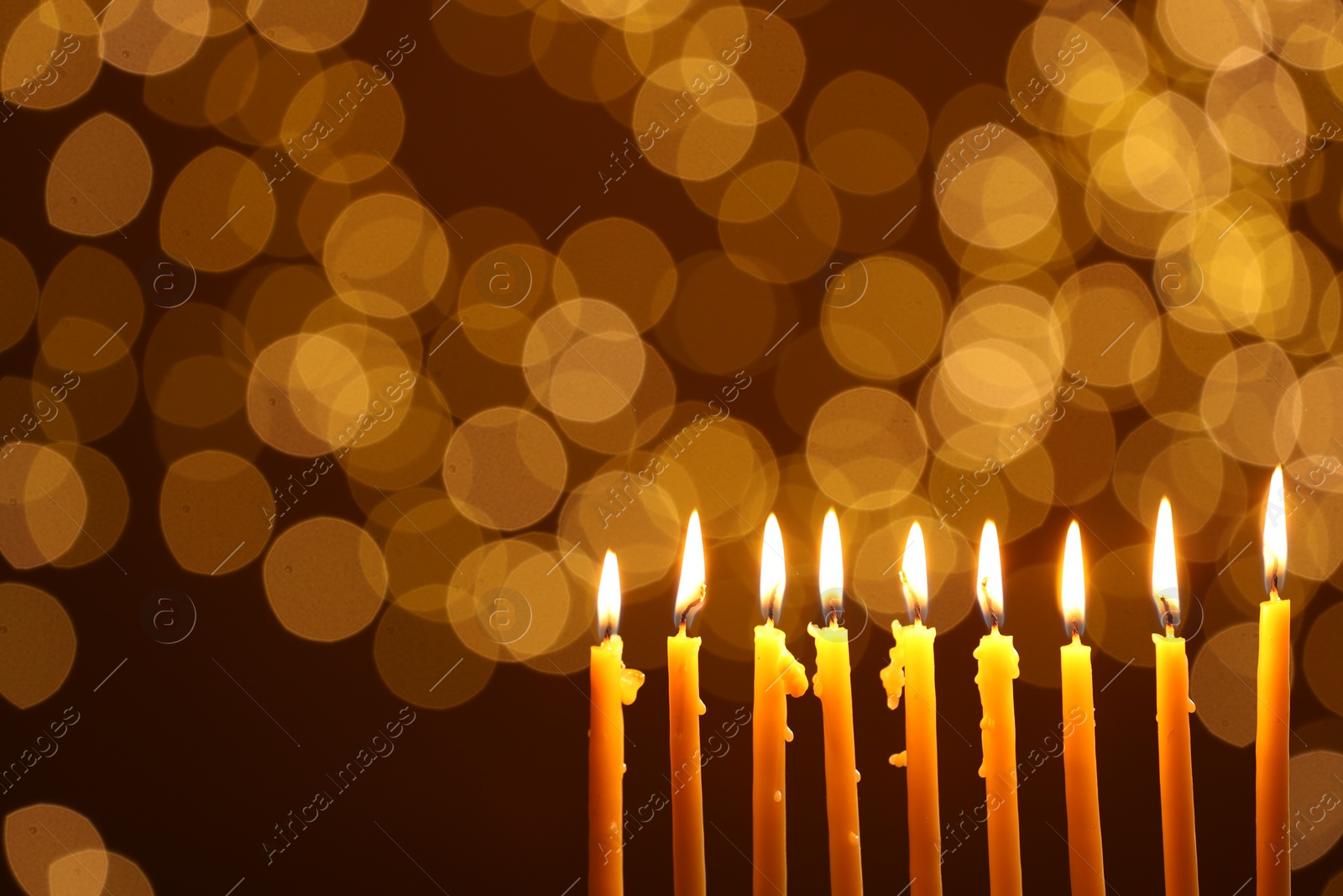 Photo of Hanukkah celebration. Burning candles against blurred lights, space for text