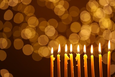 Photo of Hanukkah celebration. Burning candles against blurred lights, space for text