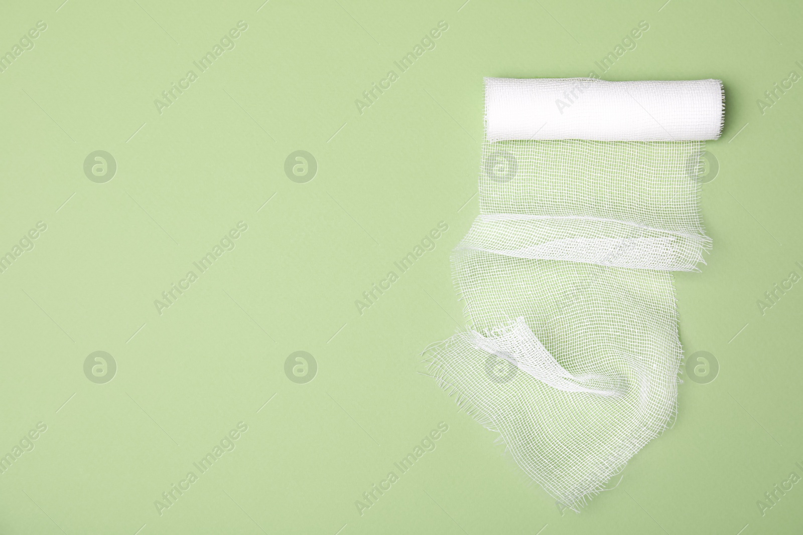 Photo of White medical bandage on light green background, top view. Space for text