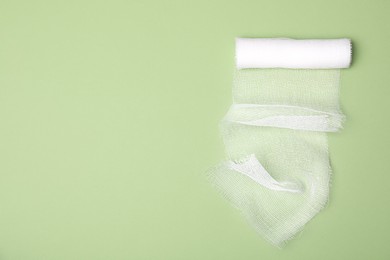 White medical bandage on light green background, top view. Space for text