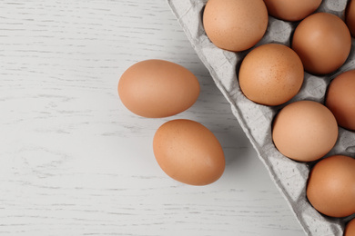 Raw chicken eggs on white wooden table, flat lay