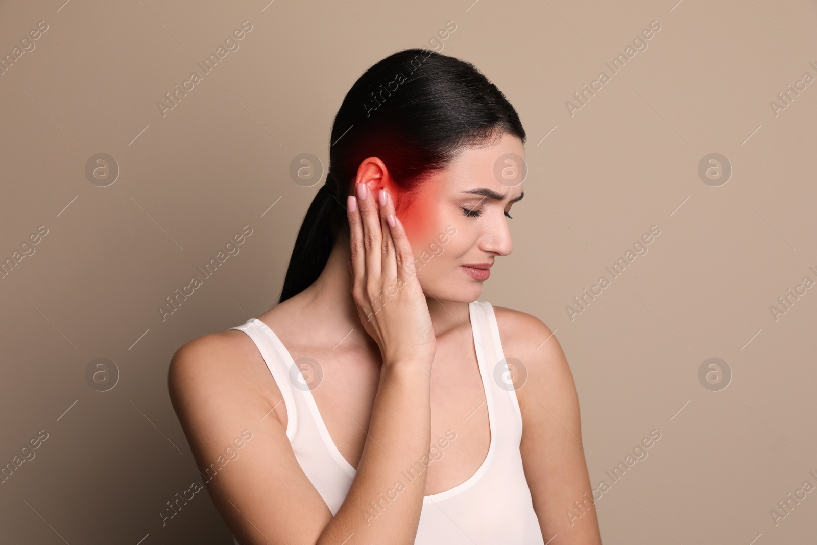 Image of Woman suffering from ear pain on beige background