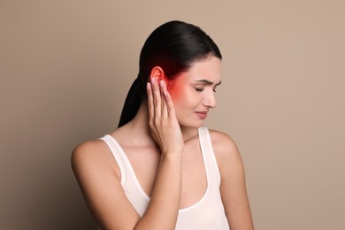 Image of Woman suffering from ear pain on beige background