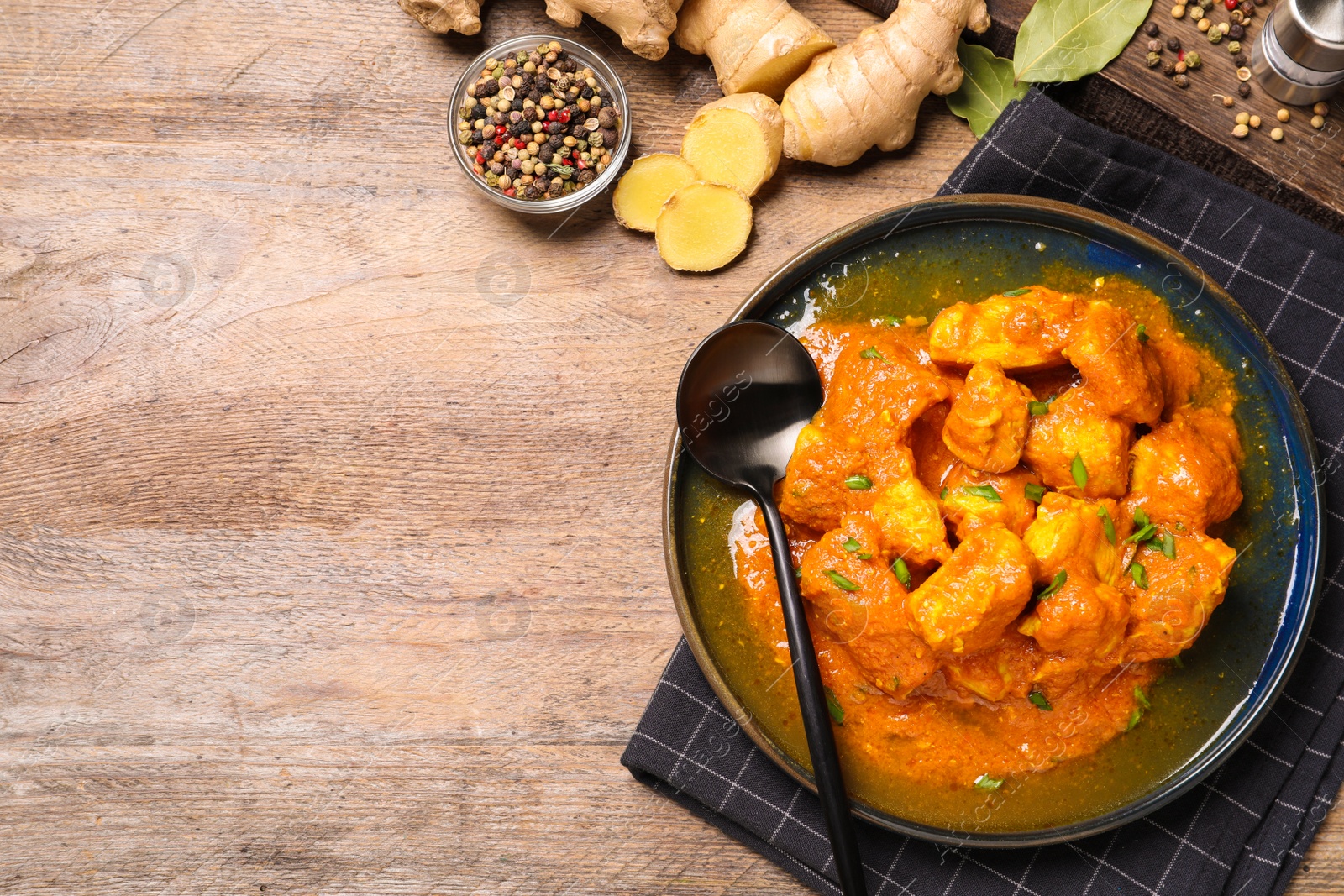 Photo of Plate of delicious chicken curry on wooden table, flat lay. Space for text