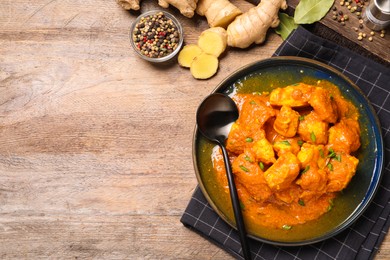 Photo of Plate of delicious chicken curry on wooden table, flat lay. Space for text