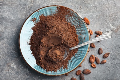 Plate with cocoa powder on grey background, top view