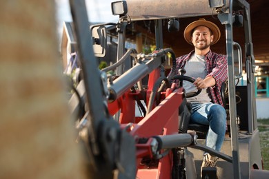 Photo of Smiling farmer in loader transporting hay outdoors