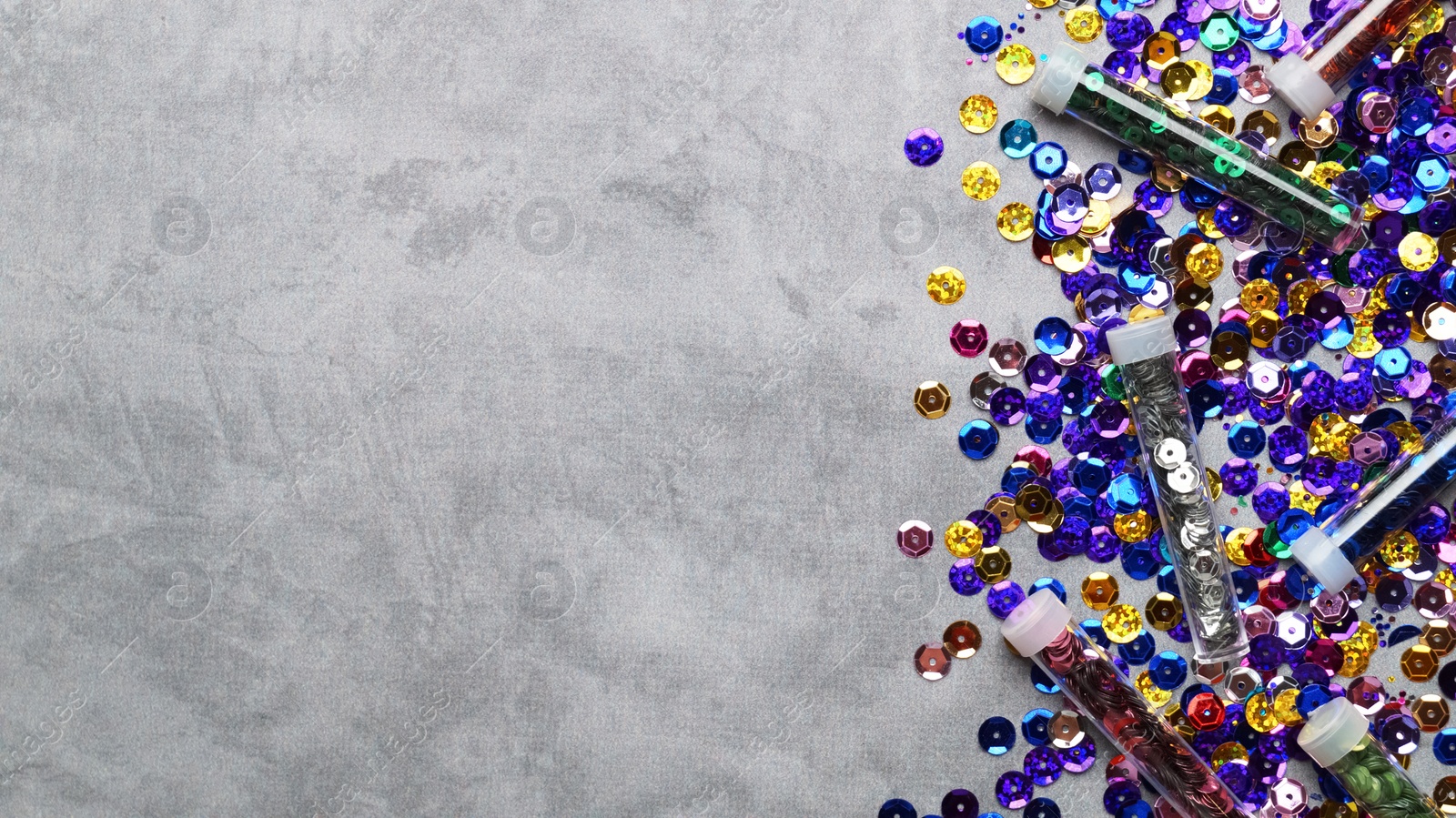 Photo of Many different shiny colorful sequins on grey background, flat lay. Space for text