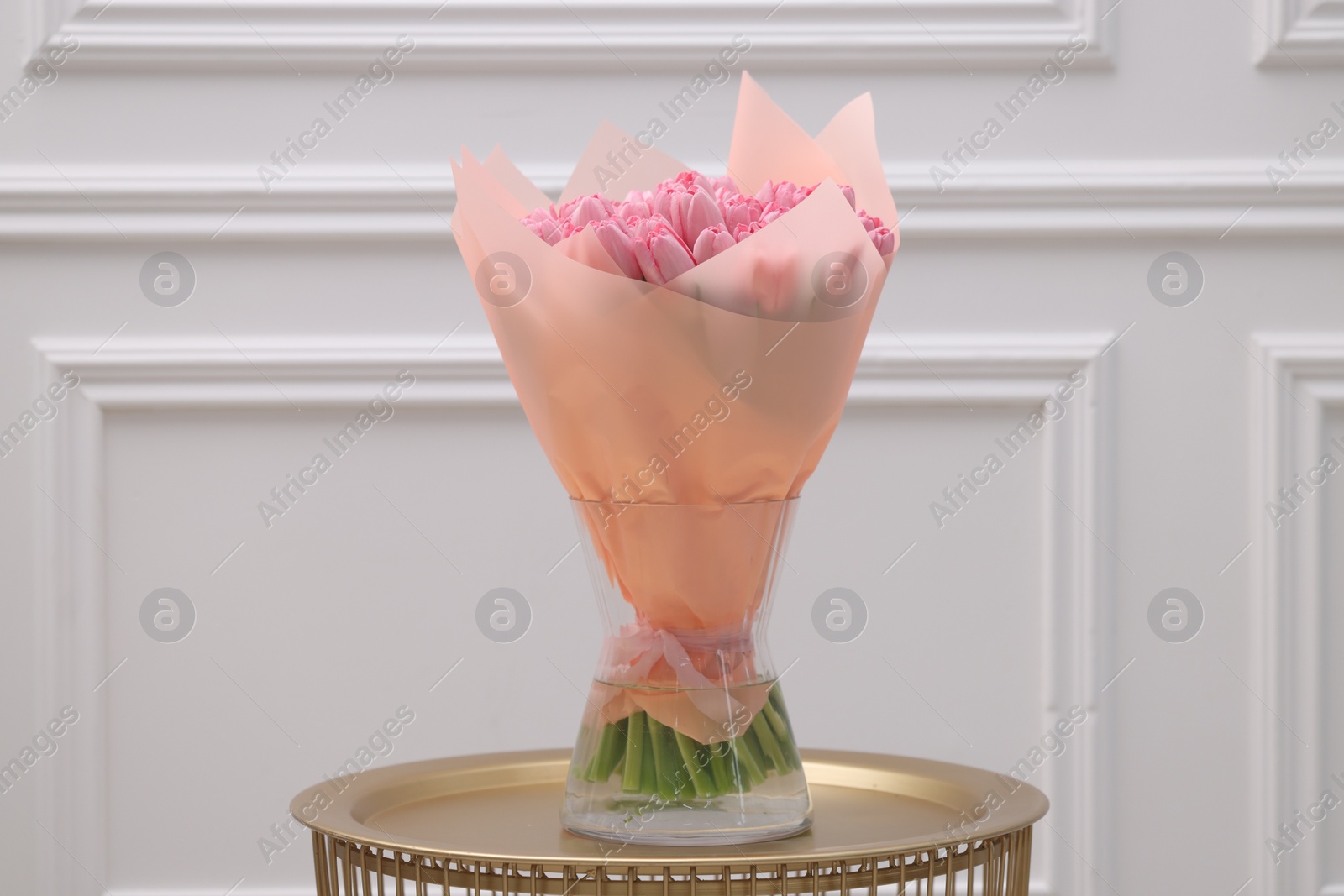 Photo of Bouquet of beautiful pink tulips in vase on table near white wall