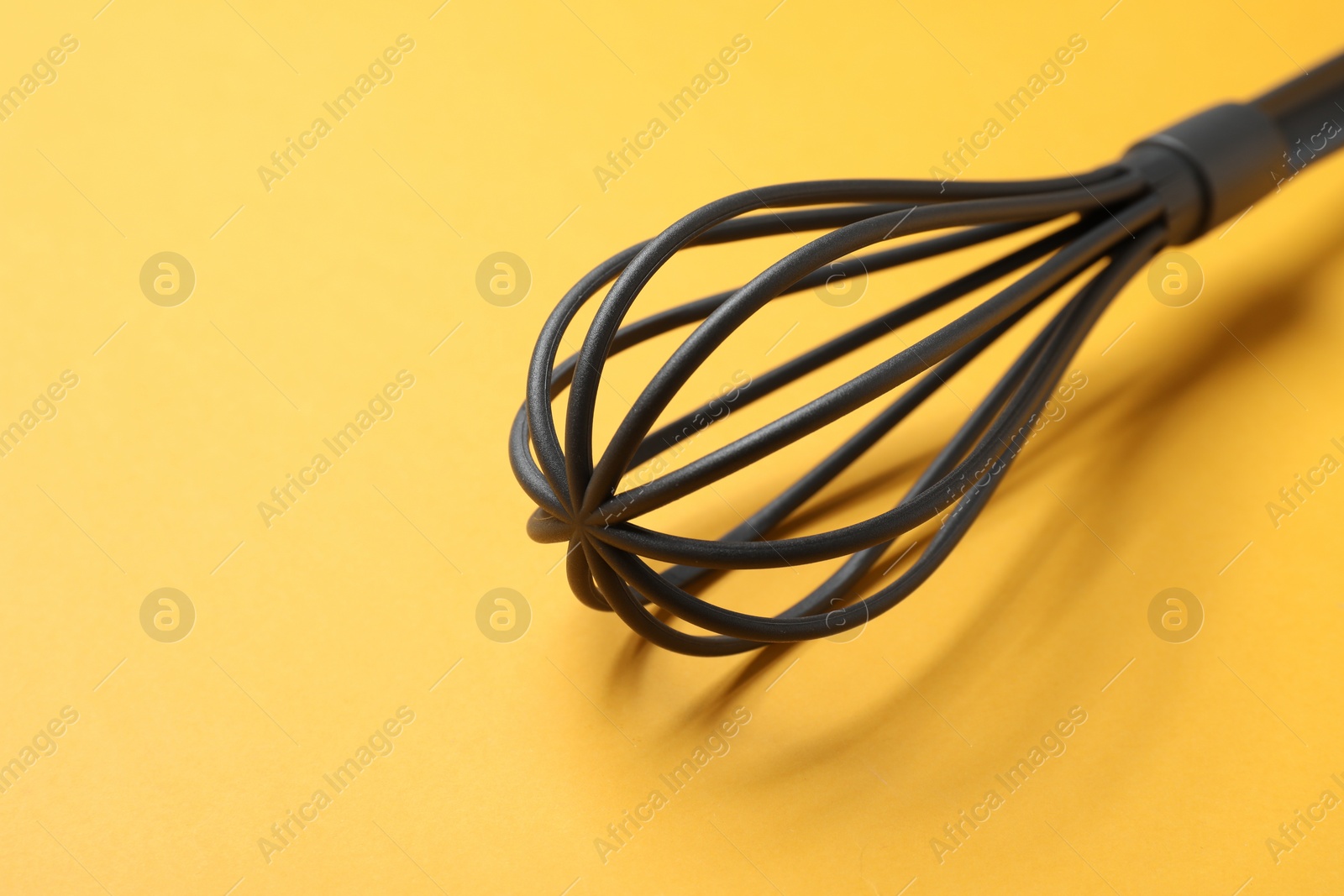 Photo of Plastic whisk on yellow background, closeup. Space for text