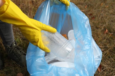 Photo of Woman with trash bag collecting garbage in nature, closeup