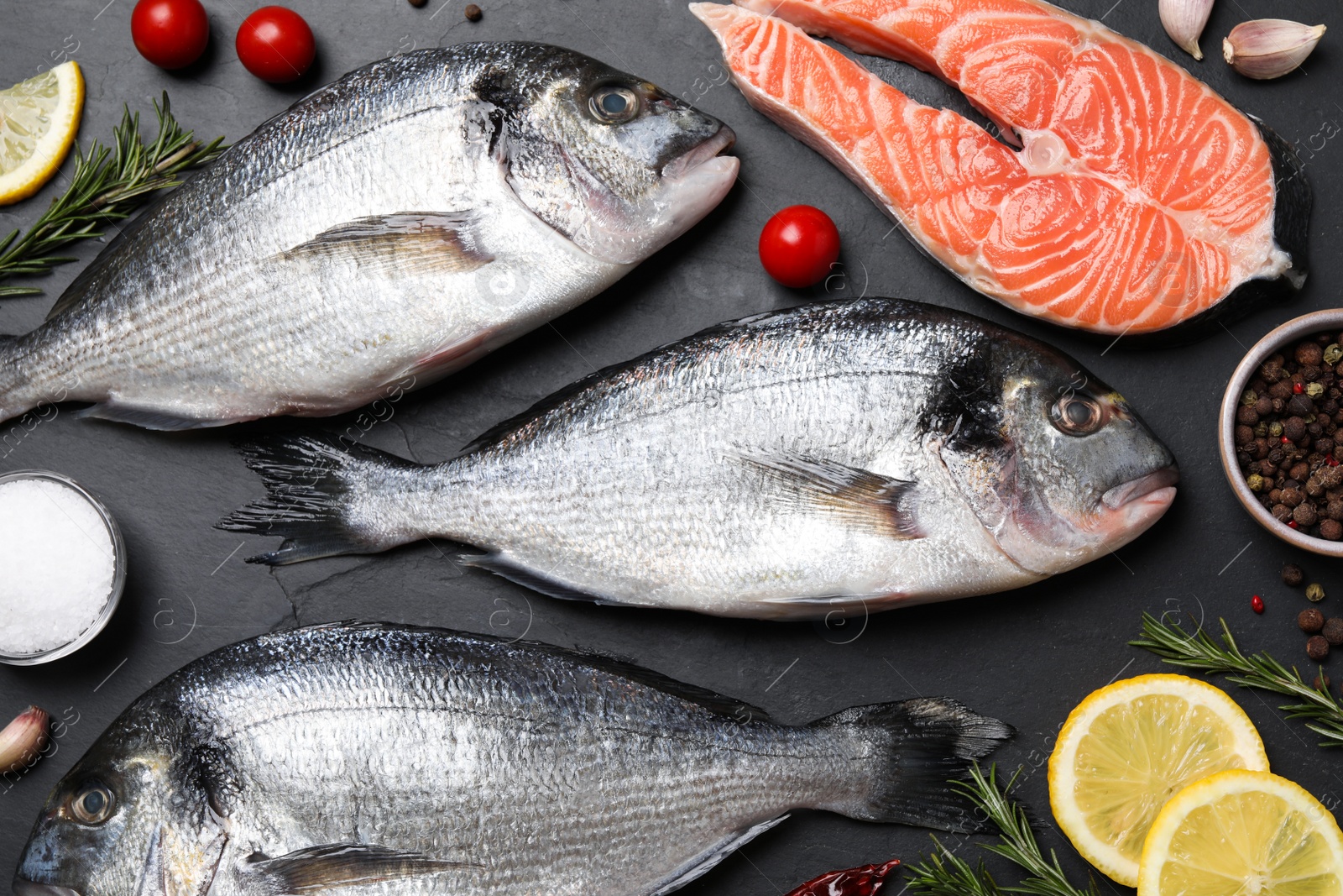 Photo of Fresh raw dorado fish, salmon and lemon slices on grey table, flat lay