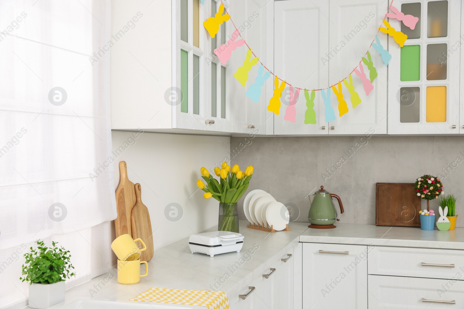Photo of Colorful Easter decor and yellow tulips in kitchen