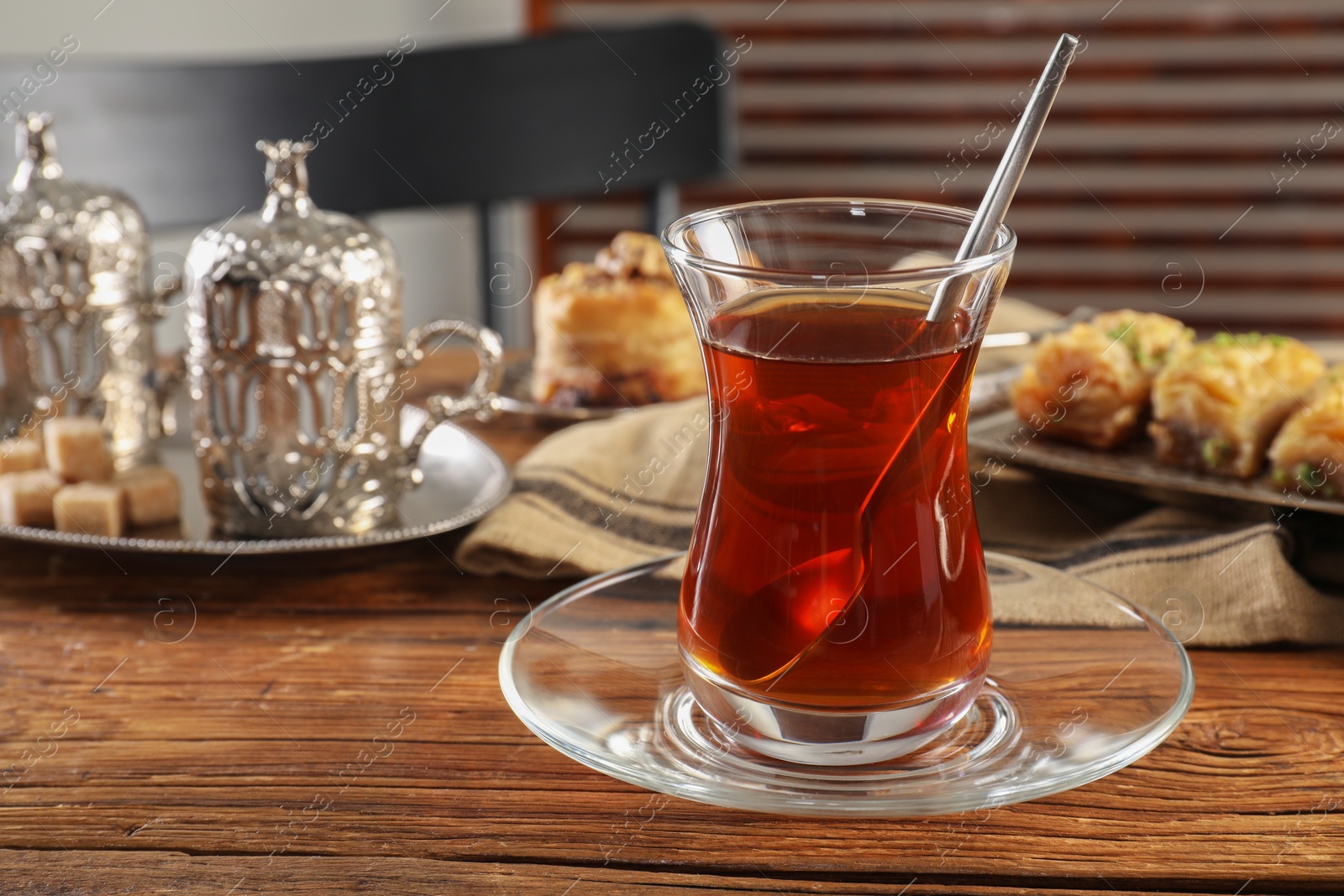Photo of Glass of traditional Turkish tea and sweets served in vintage tea set on wooden table