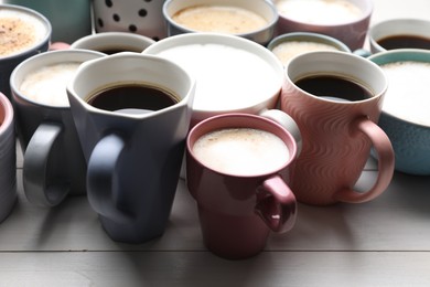 Photo of Many different cups with aromatic hot coffee on white wooden table