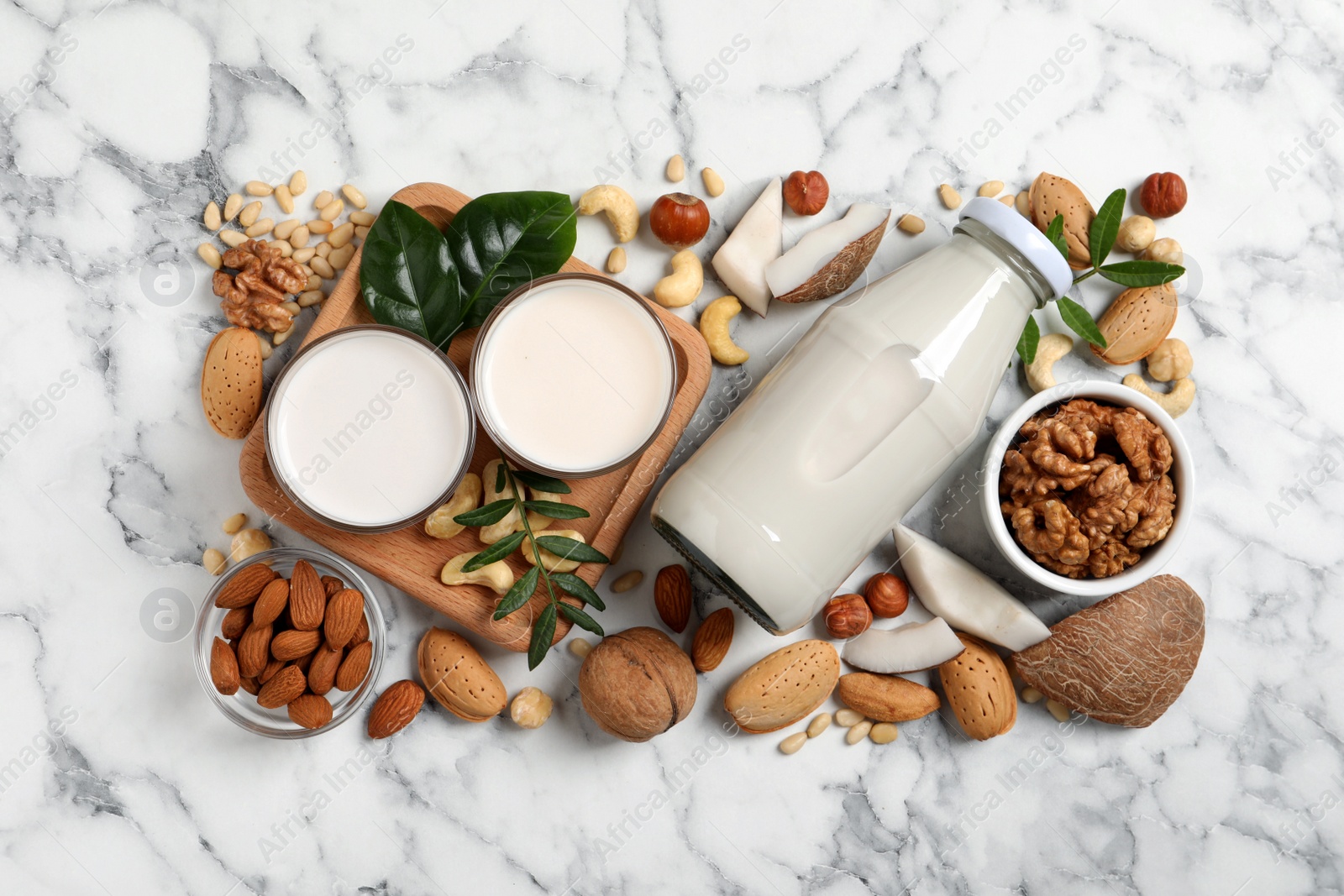 Photo of Vegan milk and different nuts on white marble table, flat lay