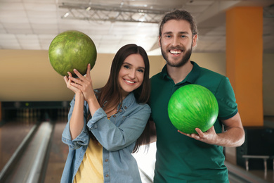 Photo of Happy young couple with balls in bowling club