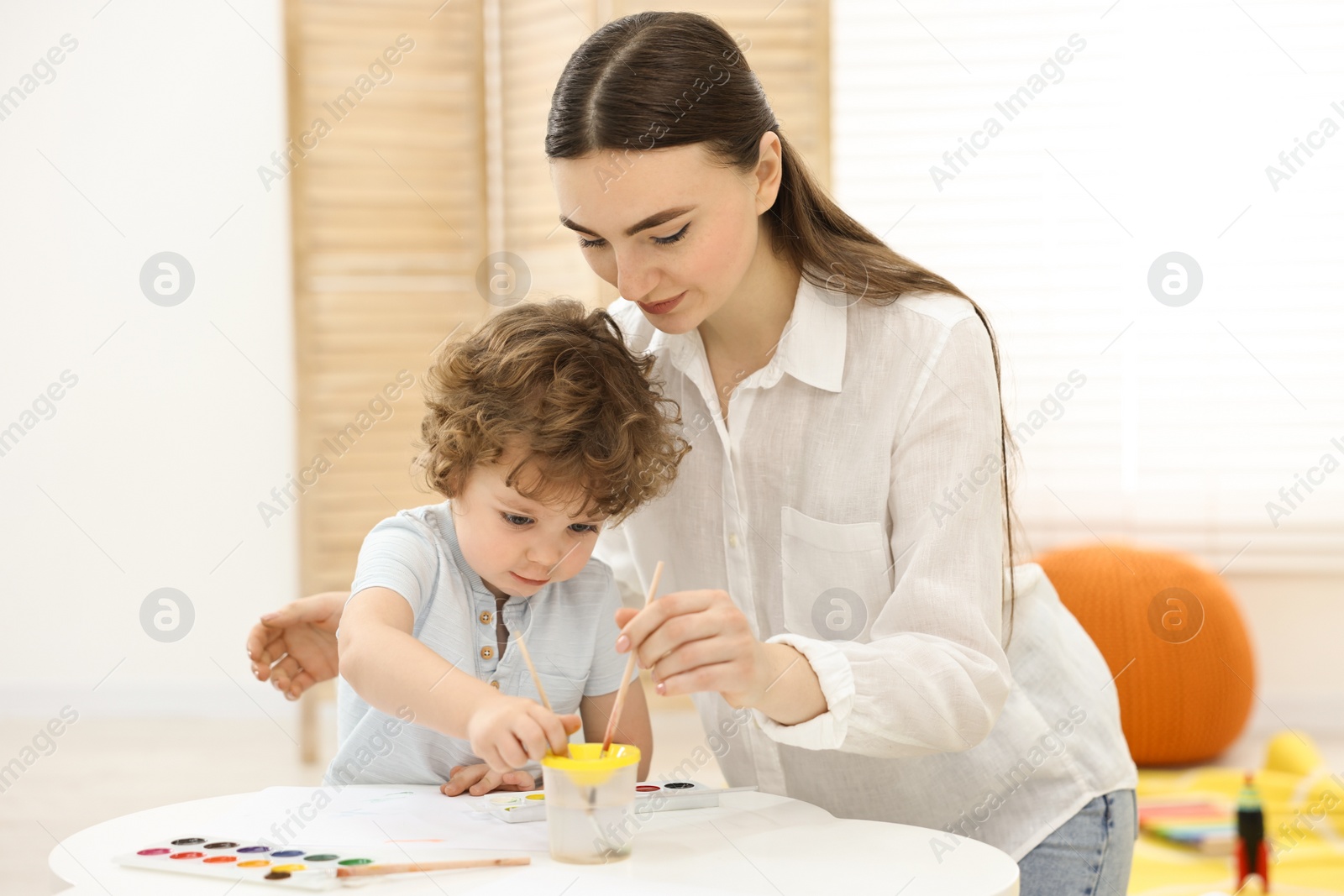 Photo of Mother and her little son painting with watercolor at home